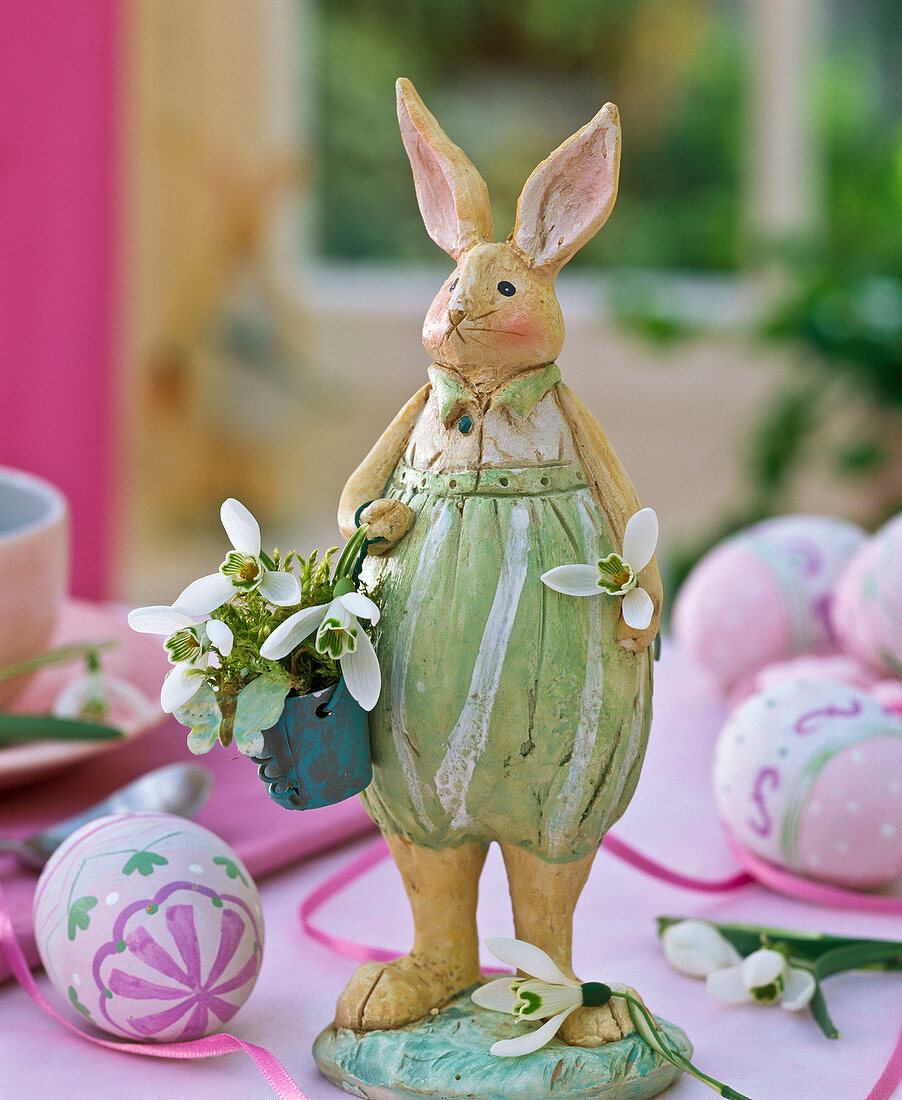 Osterhase mit Eimer gefüllt mit Galanthus (Schneeglöckchen) und Moos, Osterei