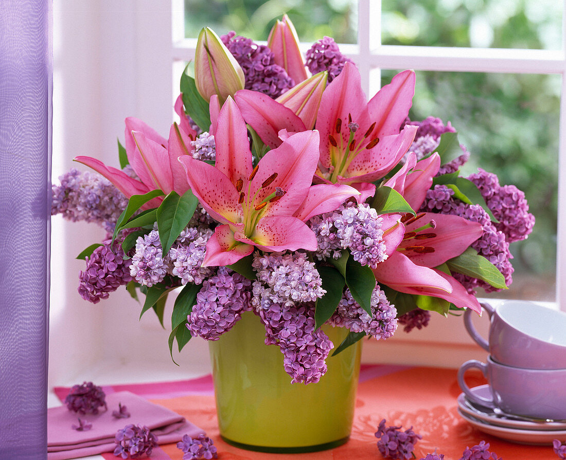 Bouquet of lilium (lily) and syringa (lilac) in green vase