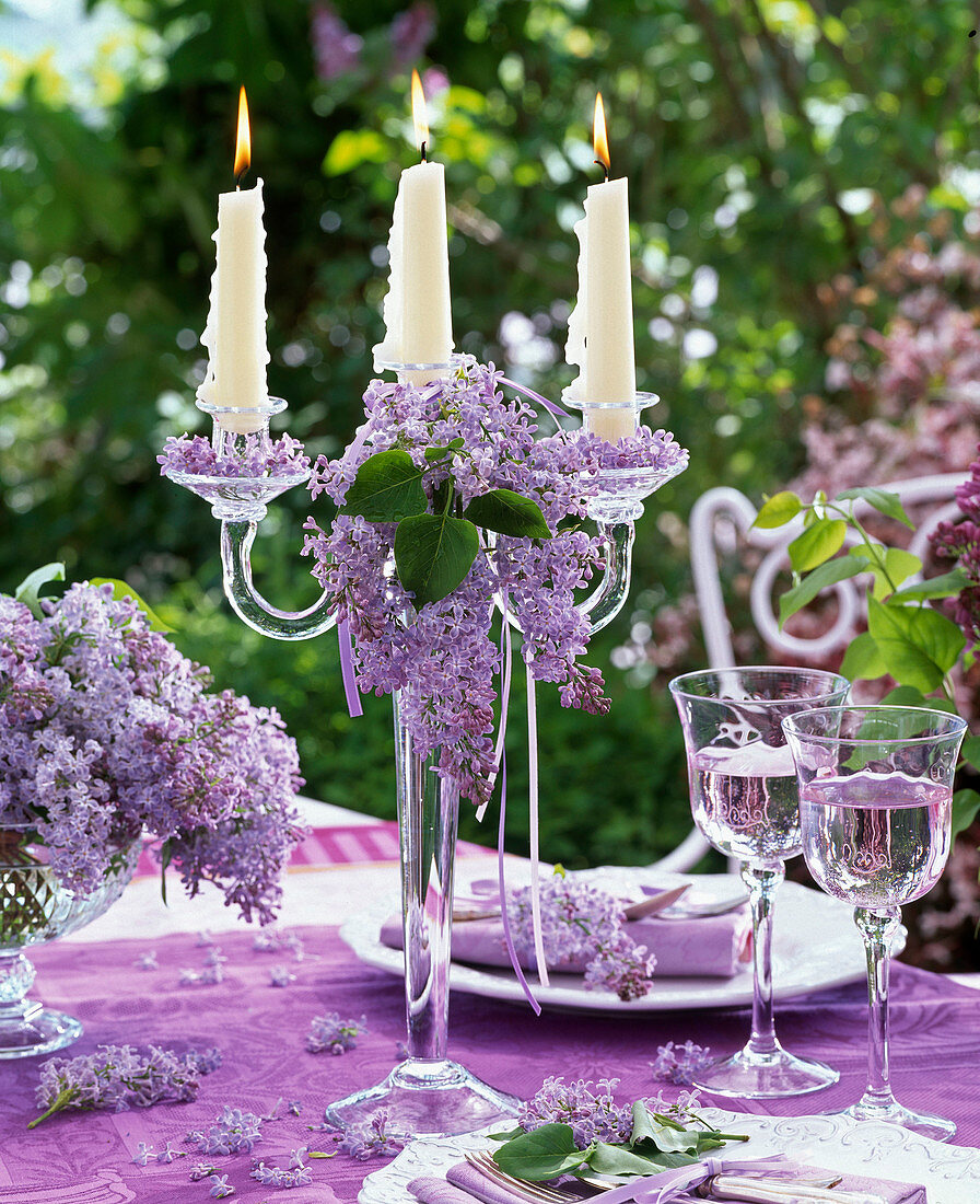 Glass candle holder decorated with syringa, drinking glasses, table settings