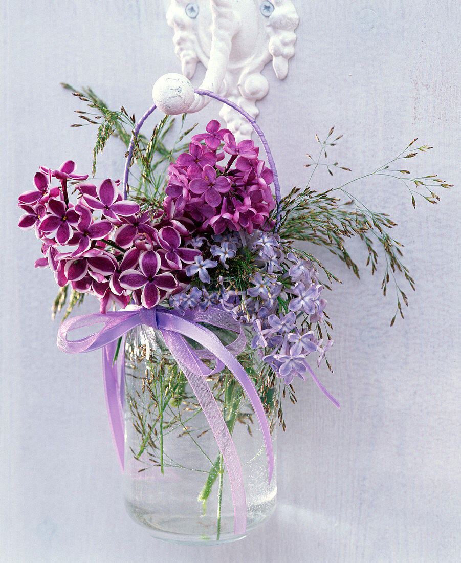 Small bouquet of different Syringa, and grasses in handle glass
