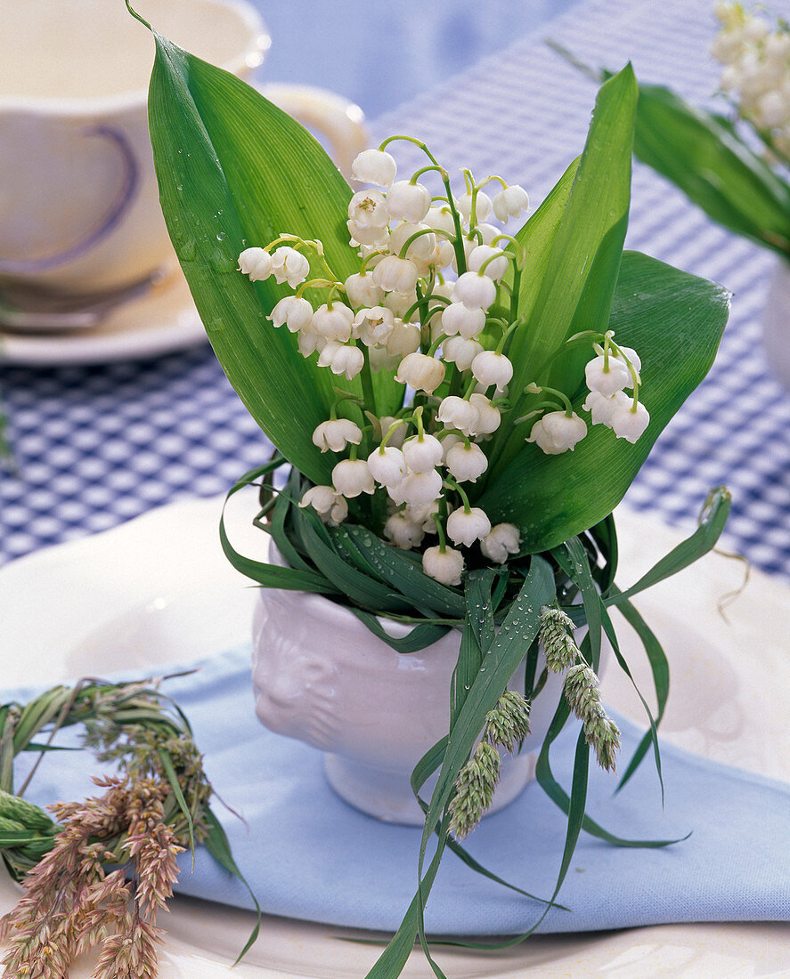 Bouquet of Convallaria and grasses in porcelain vase