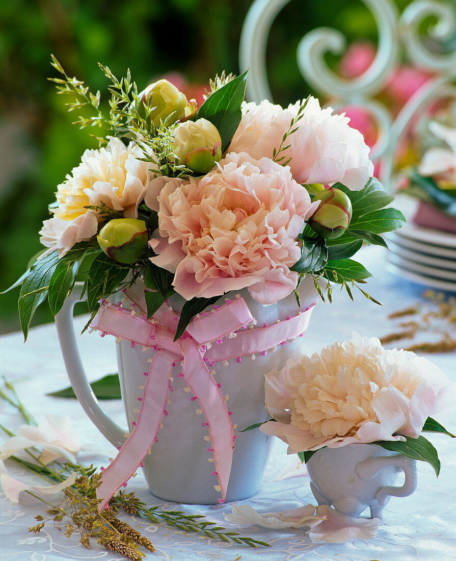 Small bouquet of salmon pink paeonia and grasses on the table