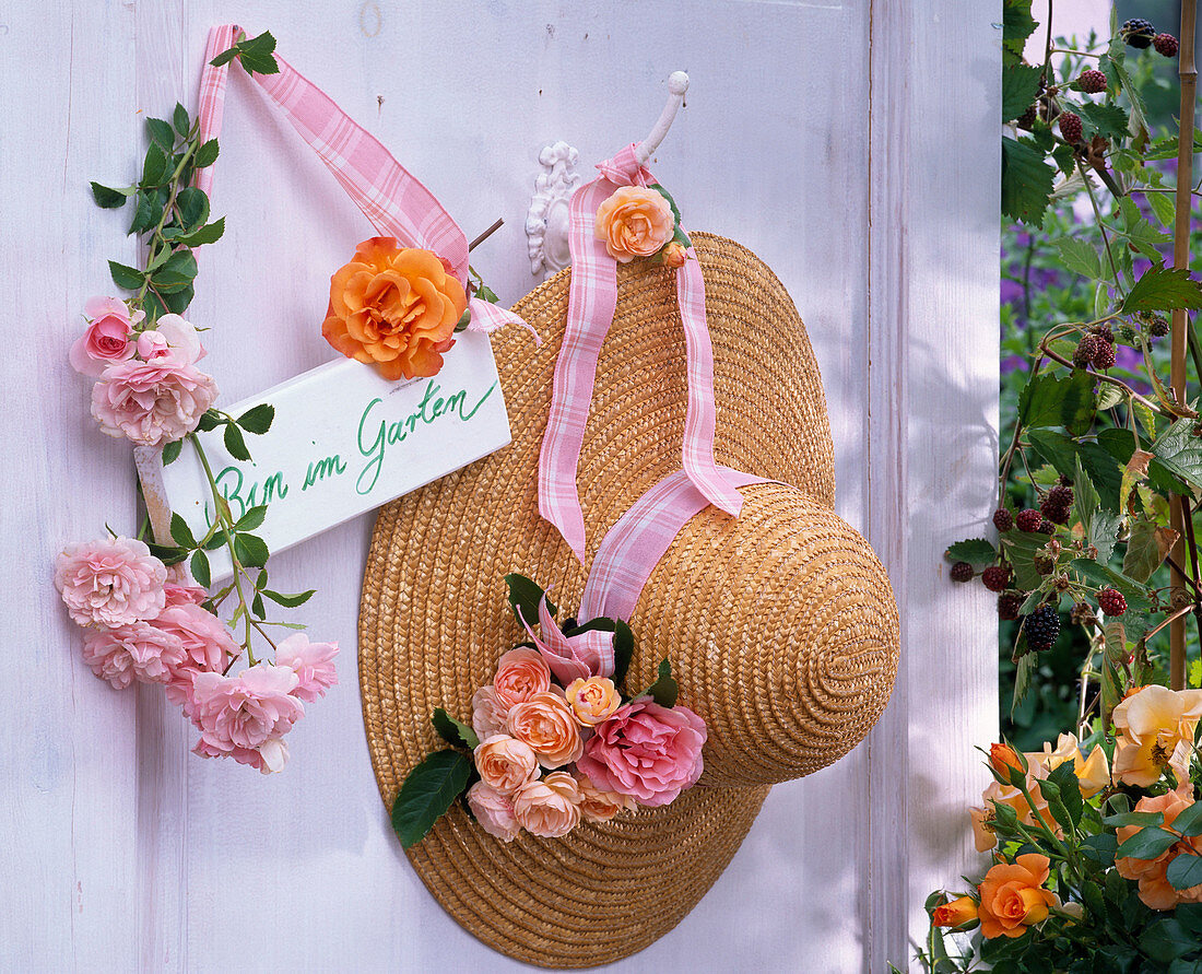 Rose on hook and straw hat, sign 'Am in the garden'