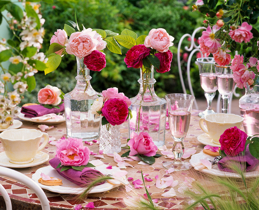 Various roses in glass bottles, on napkins and mosaic table