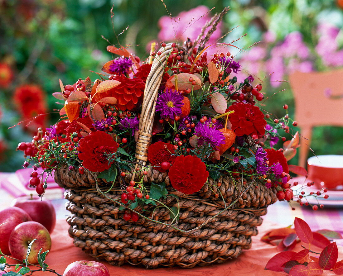 Gesteck aus Dahlia (Dahlien), Aster (Herbstastern), Hagebutten, Herbstlaub