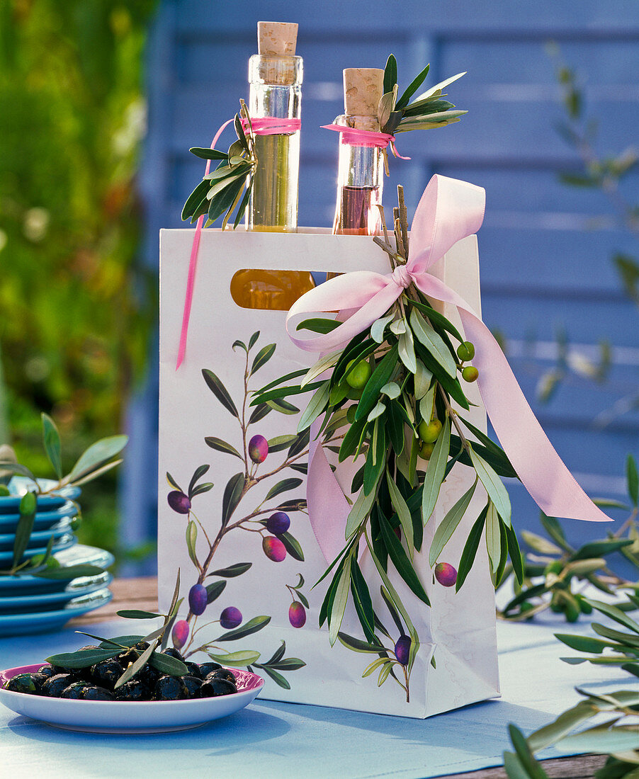 Bottles with herb oils in paper bag with olea and olives