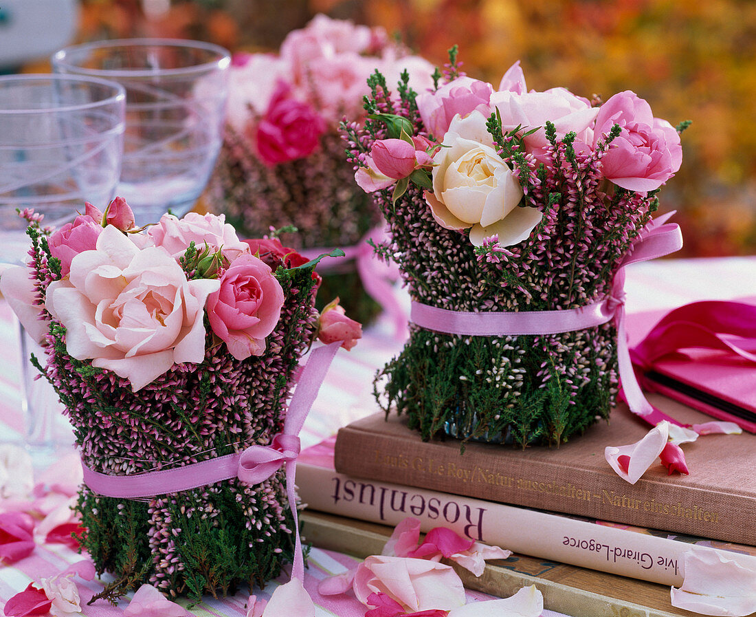 Kleine Sträuße aus Rosa (Rosen) in Vase mit Calluna (Besenheide) umwickelt