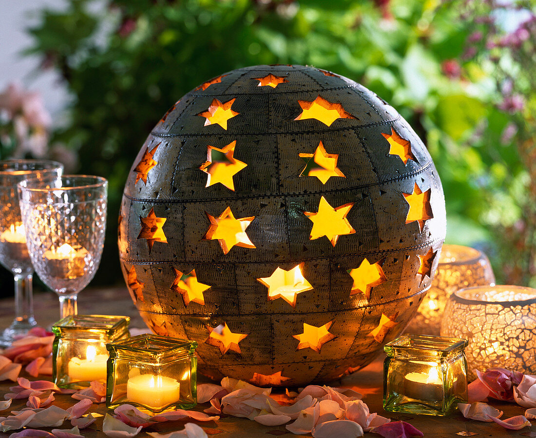 Sphere as a lantern with openings in star shape, candle glasses, petals