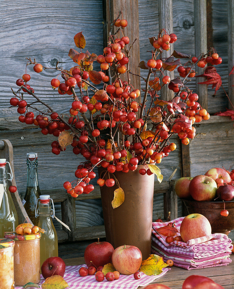 Strauß aus Malus (Zieräpfeln), Stapel mit Geschirr - Handtüchern, Flaschen