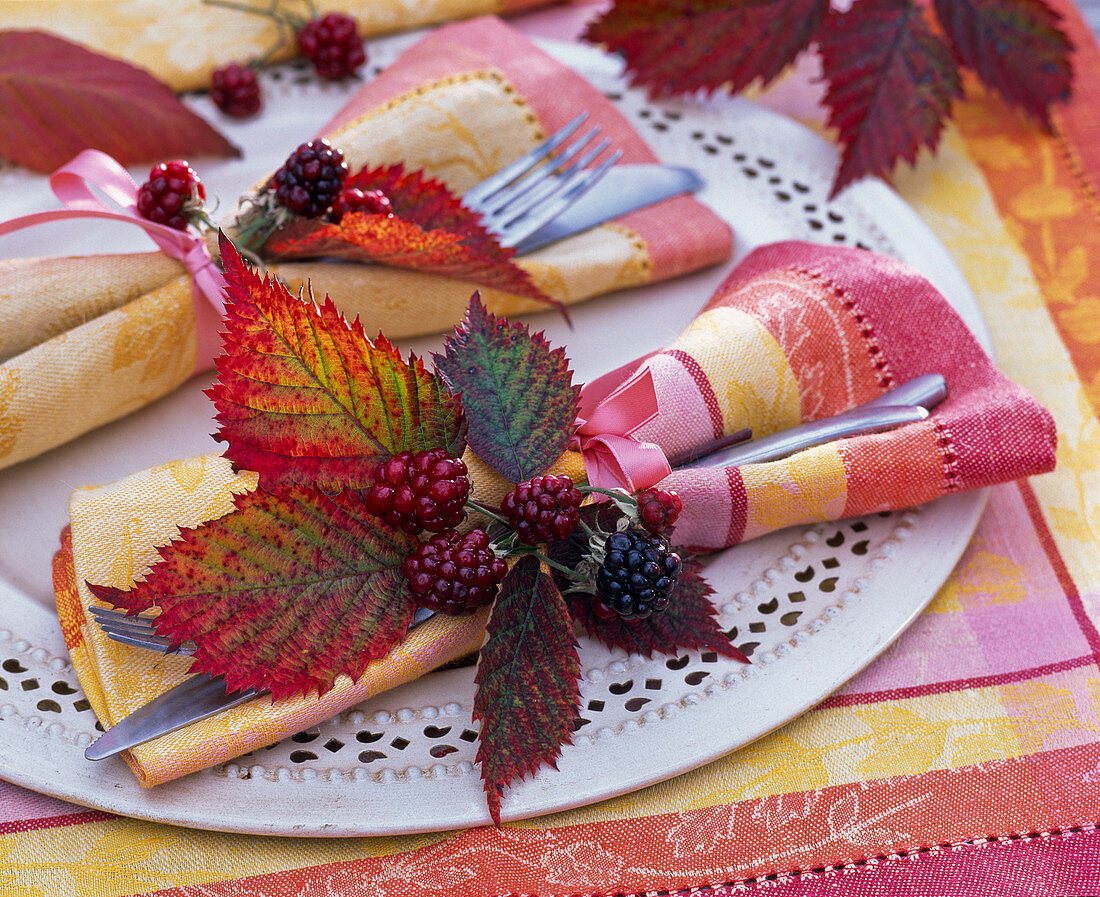 Rubus leaves and berries on patterned napkin, cutlery