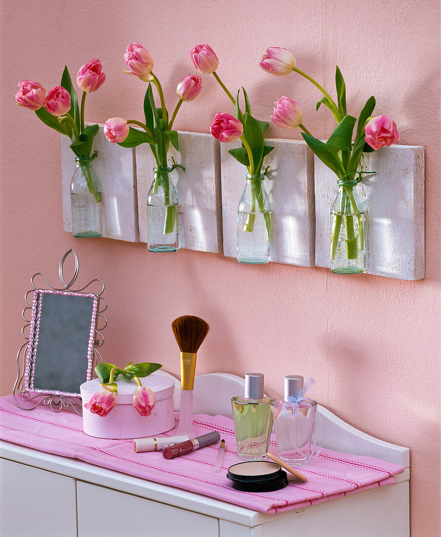 Tulipa in small bottles hanging on the bathroom wall, dressing table