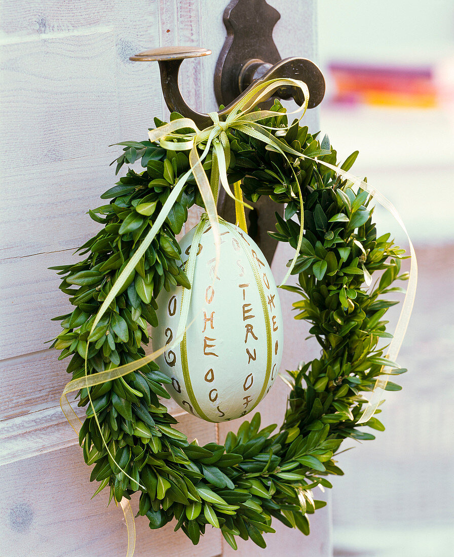 Buxus wreath with ostrich egg and text 'Frohe Ostern' at the door