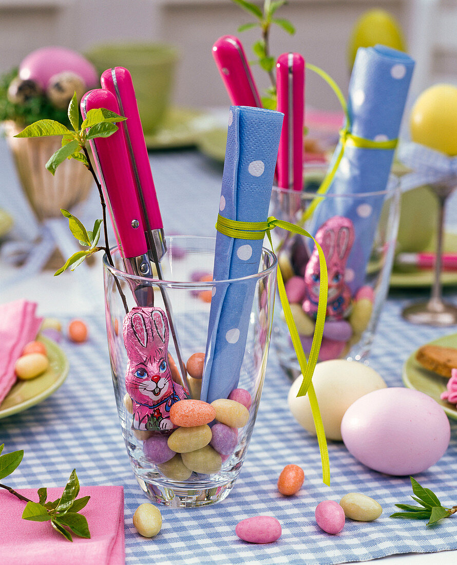 Easter table decoration with salix in glass filled with sugar eggs