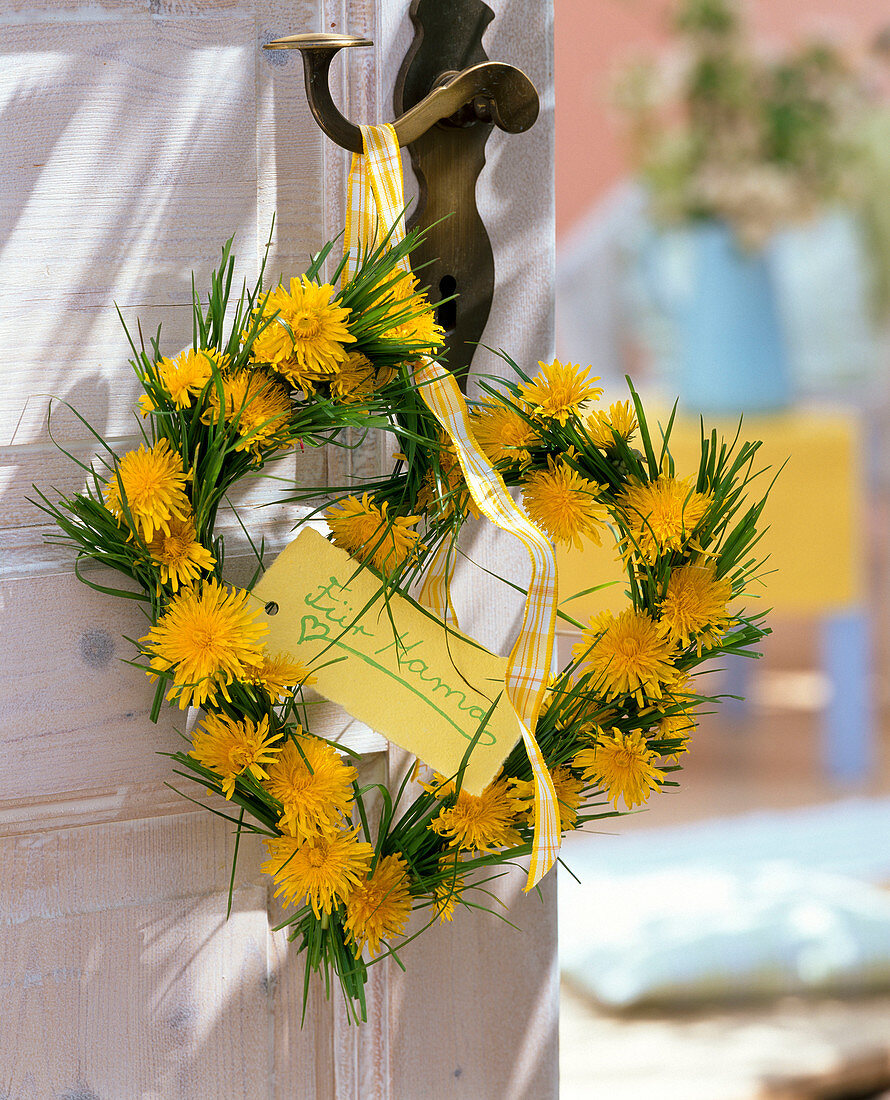 Heart-shaped taraxacum and grasses wreath on doorknob, sign