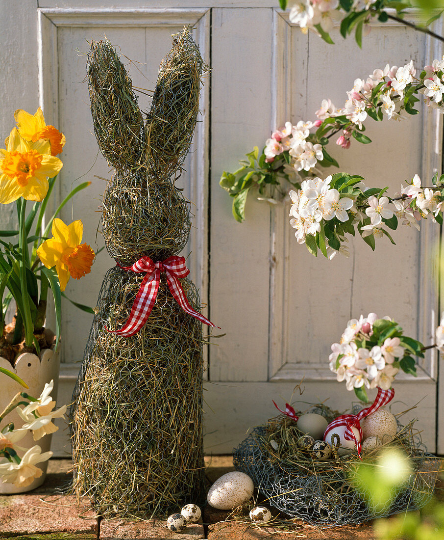 Osterdekoration auf der Terrasse mit Osterhasen aus Stroh, Osternest, Narcissus