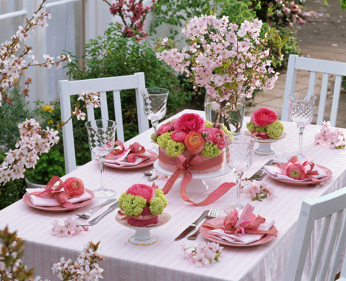 Tischdekoration mit Ranunculus (Ranunkeln), Viburnum (Schneeball), Prunus