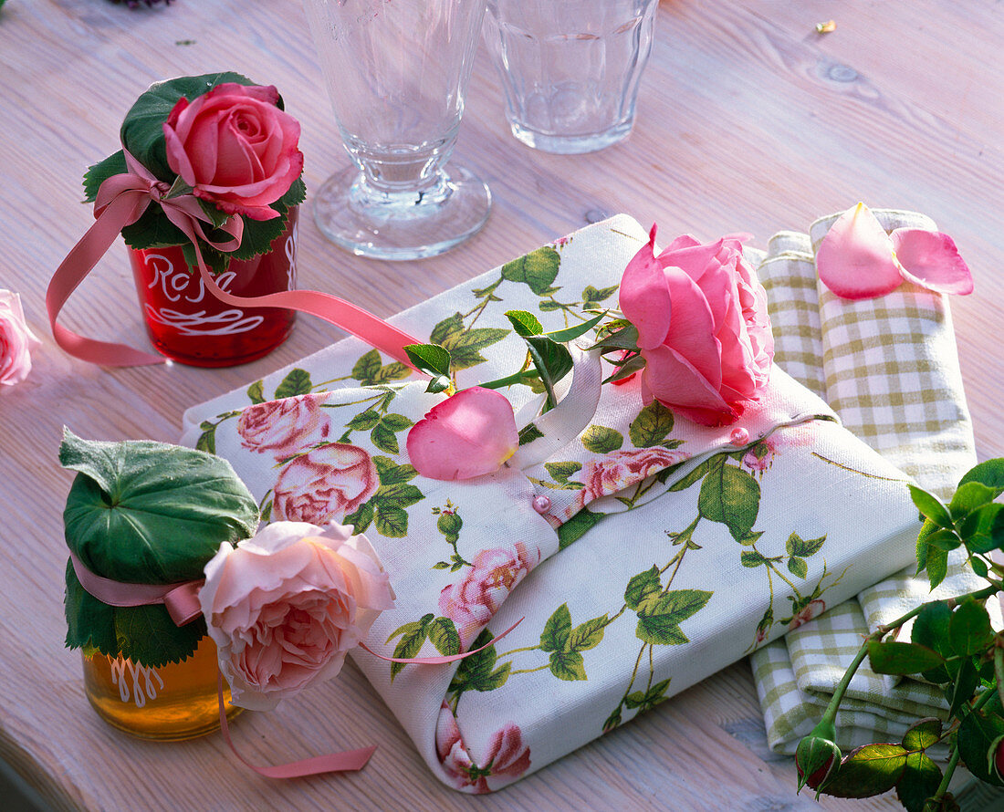Rosa (Rosen) an und um Geschenk in Tuch mit Rosenmotiven eingepackt