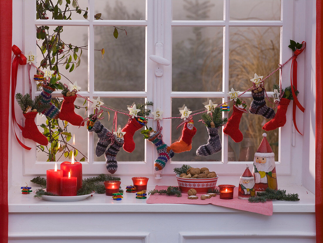 Advent calendar made of baby socks hanging on cord at the window