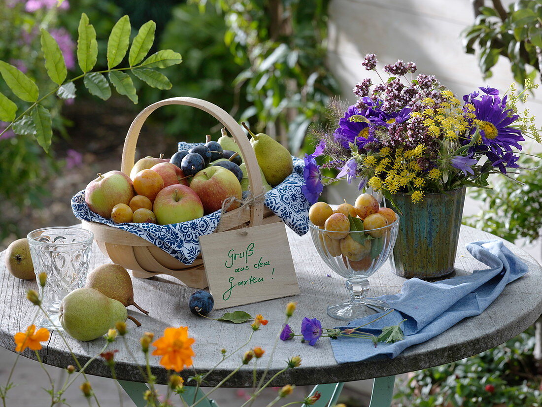 Basket with apples, plums, pears, mirabelles, herb bouquet