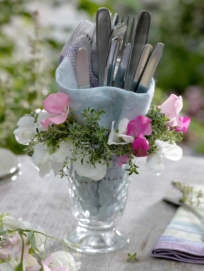 Small wreath of sweet pea and lemon thyme around glass with cutlery