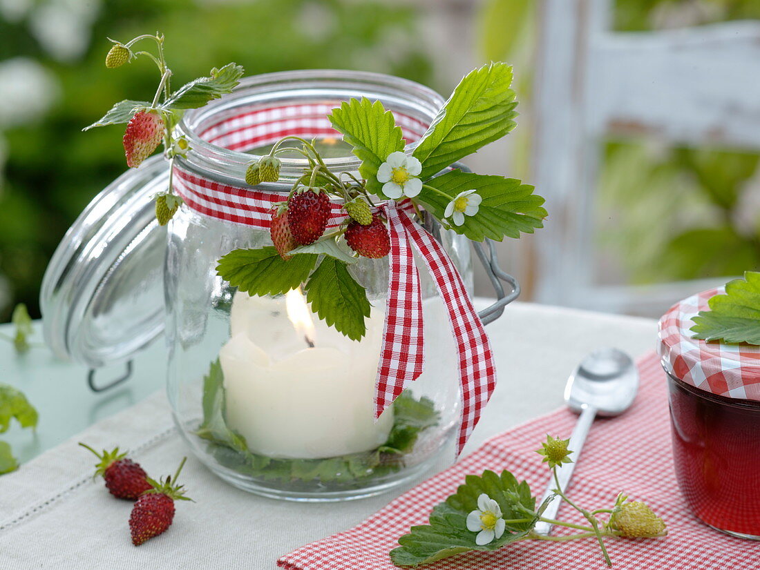 Deckelglas mit kleinem Sträußchen aus Walderdbeeren als Windlicht