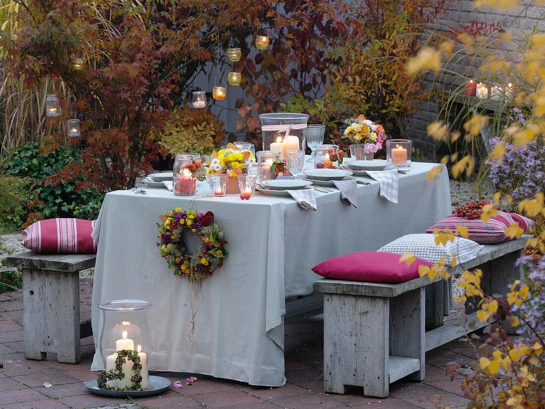 Herbstlich gedeckter Tisch mit Sträussen aus Rosen und Chrysanthemen