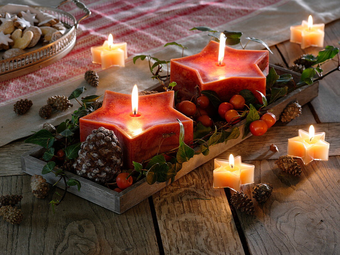Red star candles with cones, ornamental apples and hedera