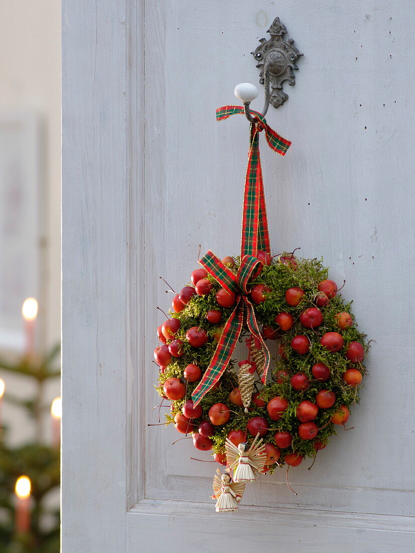 Door wreath made of moss and ornamental apples with angels and tree decorations