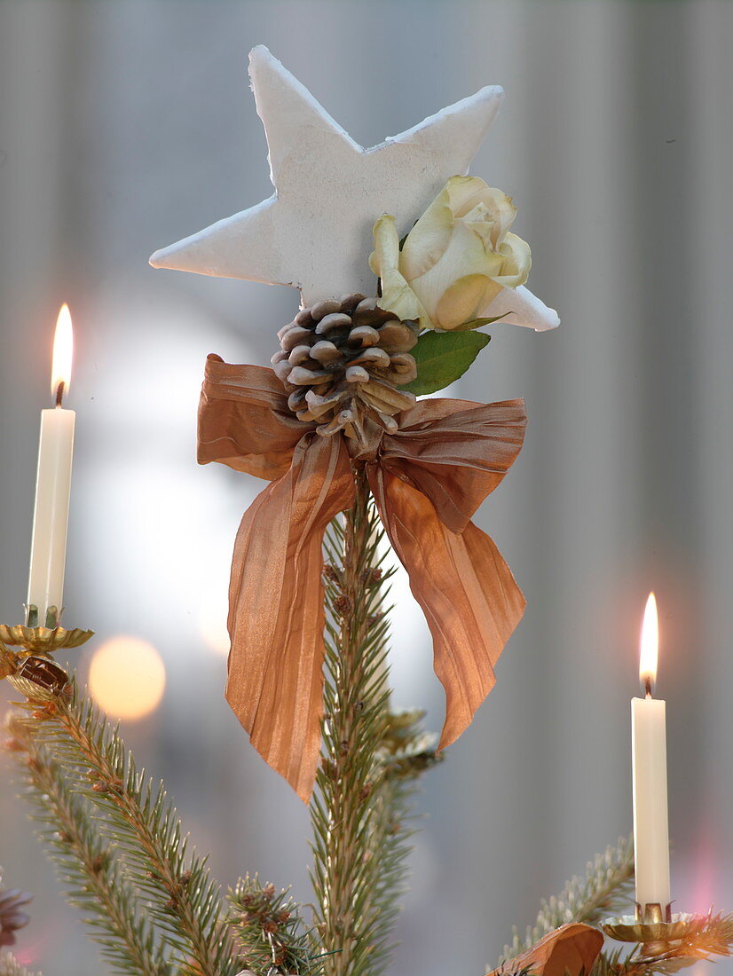 Mit Rosenblüten und Zapfen geschmückte Blaufichte als Weihnachtsbaum