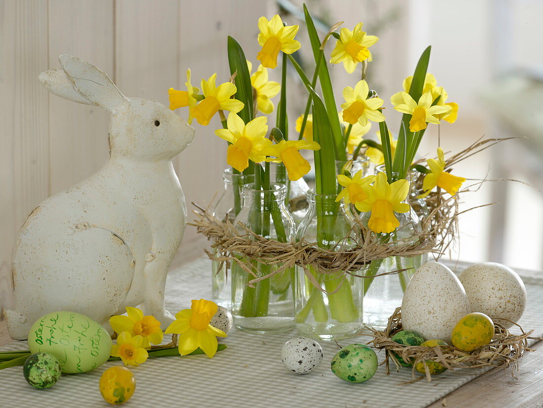 Narcissus 'Tete a Tete', small bottles as vases in a straw wreath