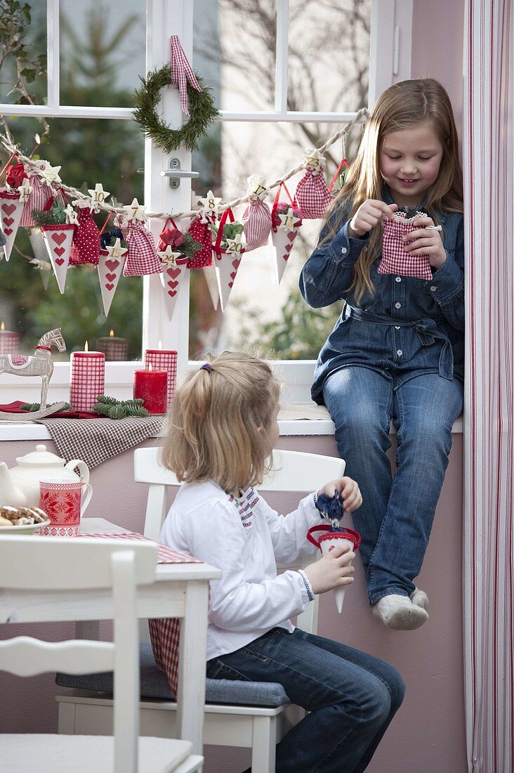 Mädchen mit Adventskalender am Fenster