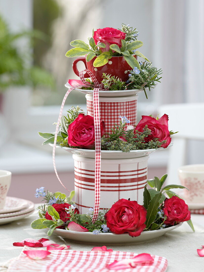 Aus Tellern, Tasse und Dosen selbstgebaute Etagere mit Rosen und Kräutern