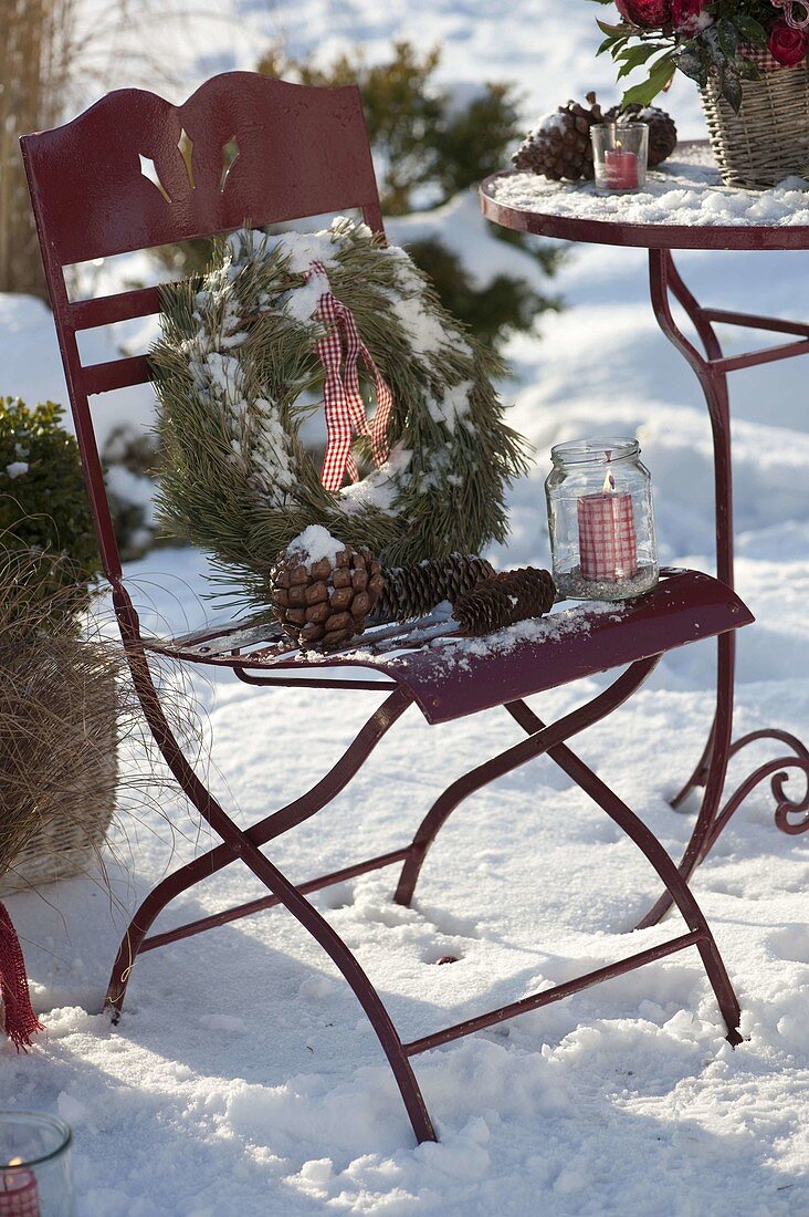Stuhl auf verschneiter Terrasse weihnachtlich dekoriert