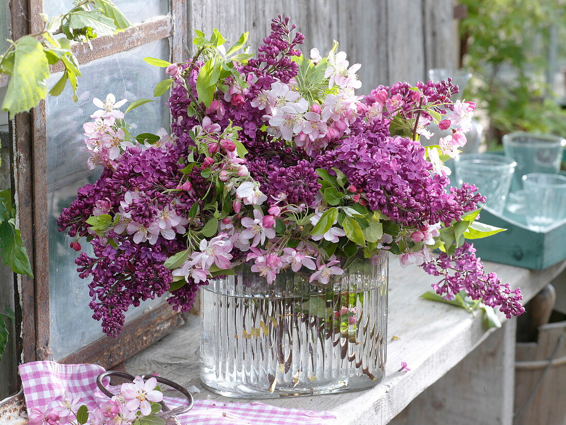 Malus flowers and syringa bouquet in glass vase