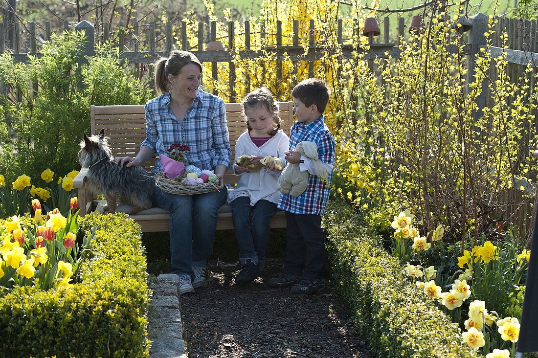 Frau und Kinder mit Osternest im Bauerngarten