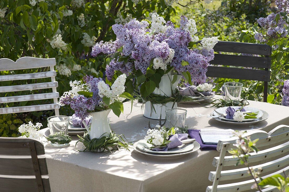 Lilac table decoration in the garden in front of lilac bushes