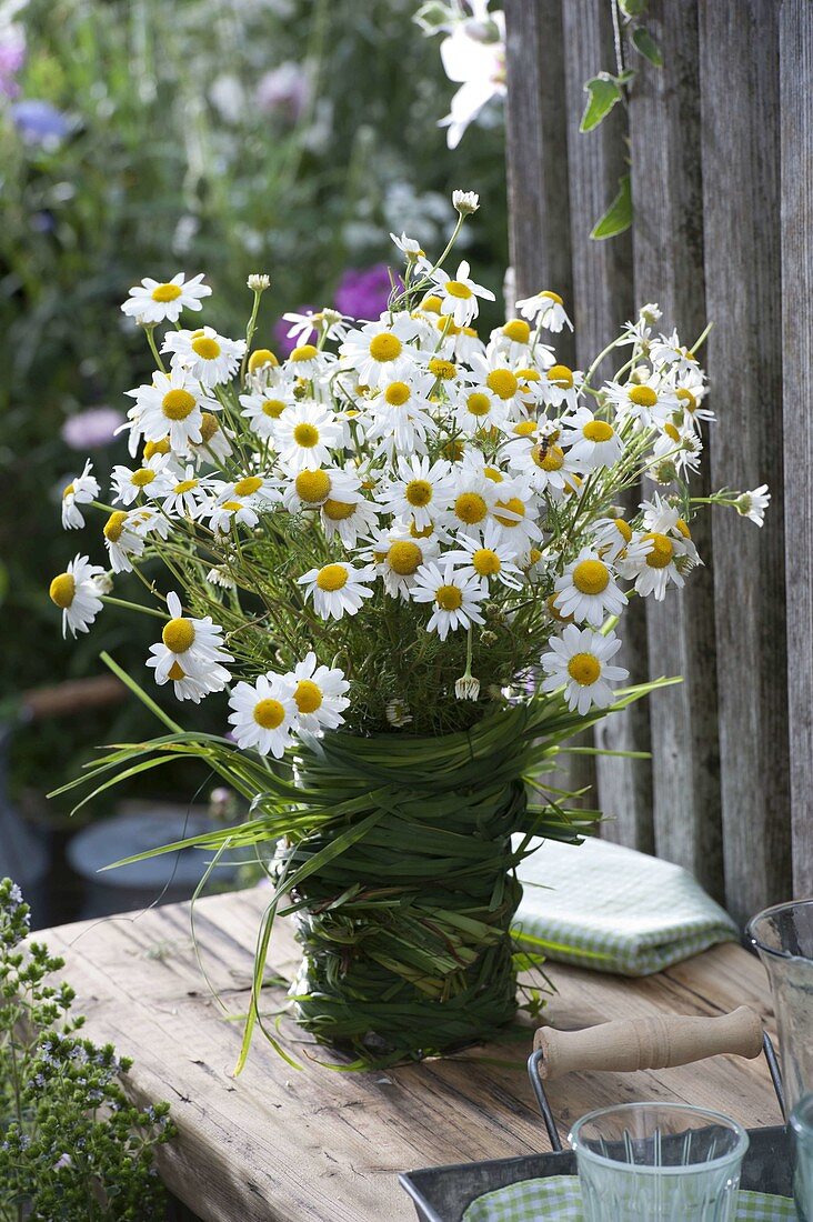 Camomile bouquet in grass-wrapped vase