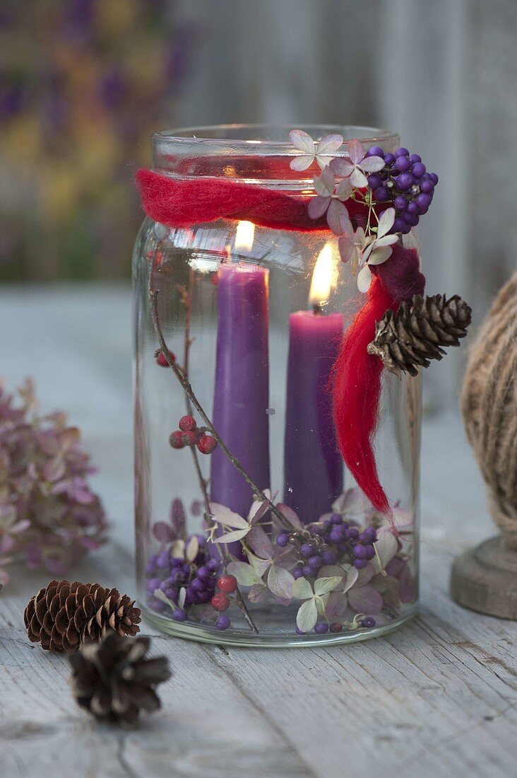 Einmachglas mit violetten Kerzen als Windlicht, dekoriert mit Beeren