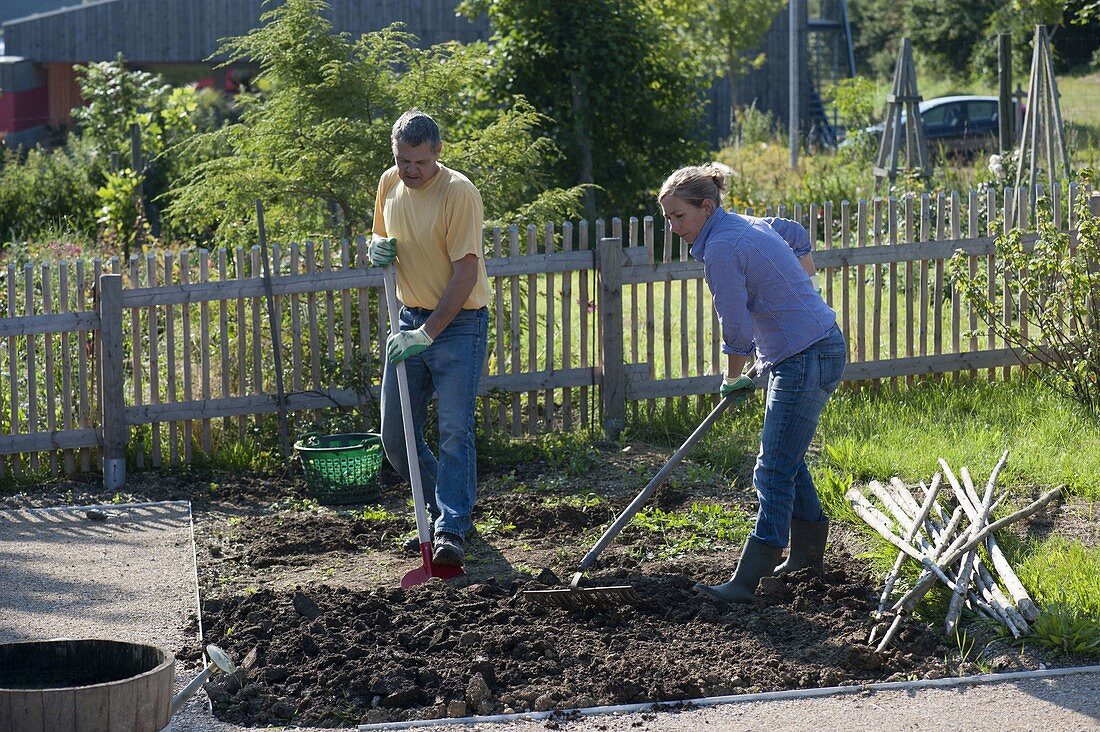 Woman and man cleaning flower beds for the new plant