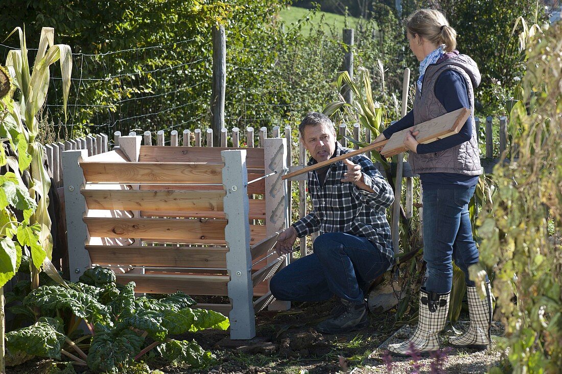 Mann und Frau bauen zusammen Kompost-Behälter auf