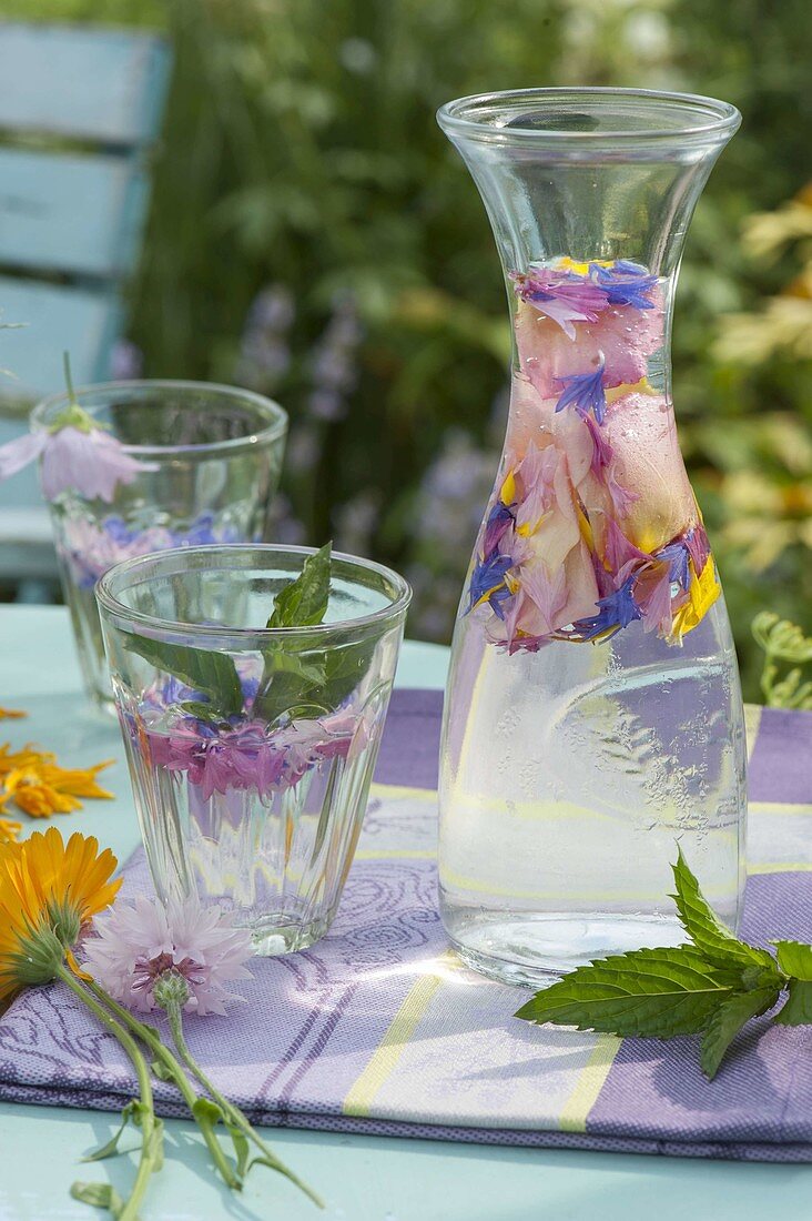 Stilles Wasser mit Minze (Mentha) und Blüten als Getränk