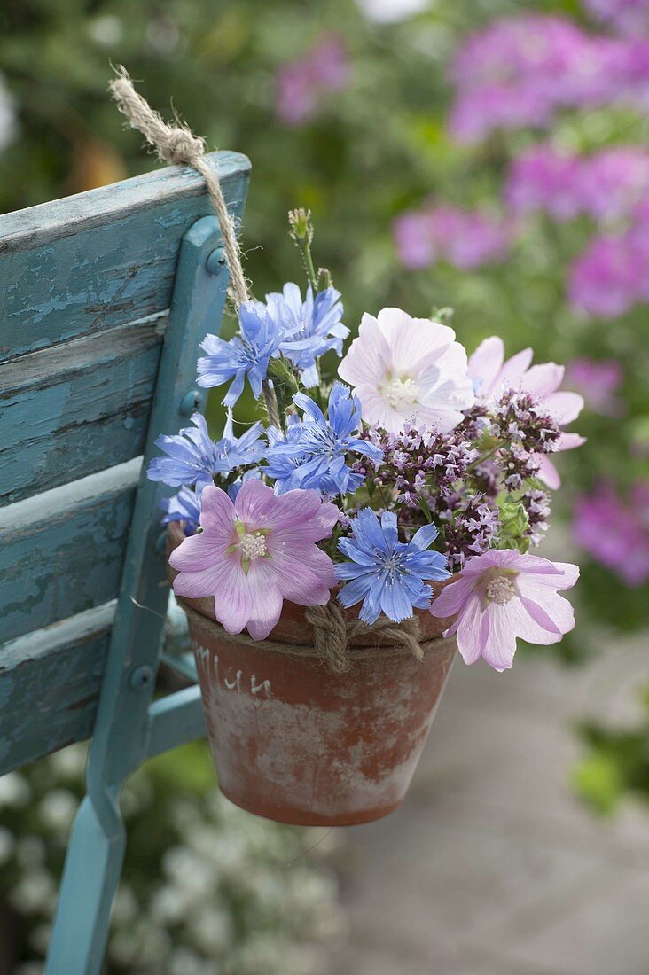 Small meadow bouquet in clay pot hanged on chair back