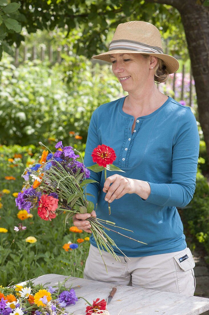 Frau bindet bunten Sommerblumenstrauss
