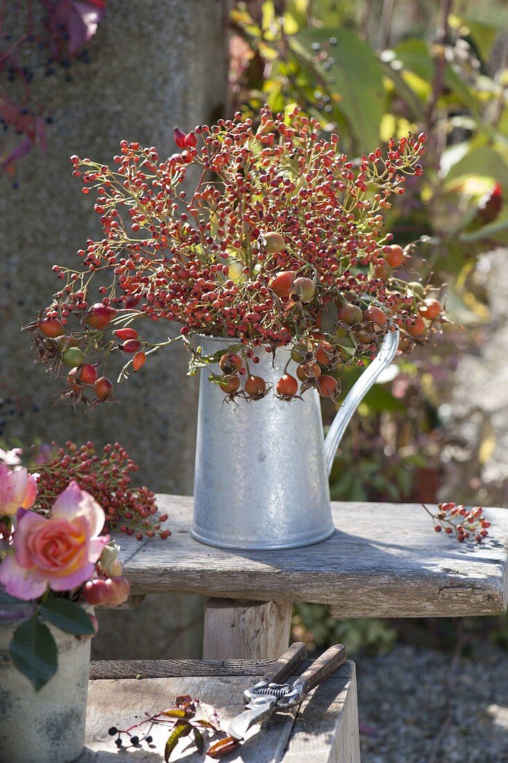Bouquet with pink, large and small rosehips in zinc can