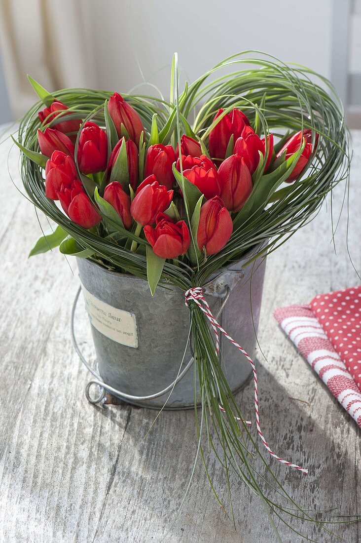 Valentinstrauss aus roten Tulpen im Gras-Herz