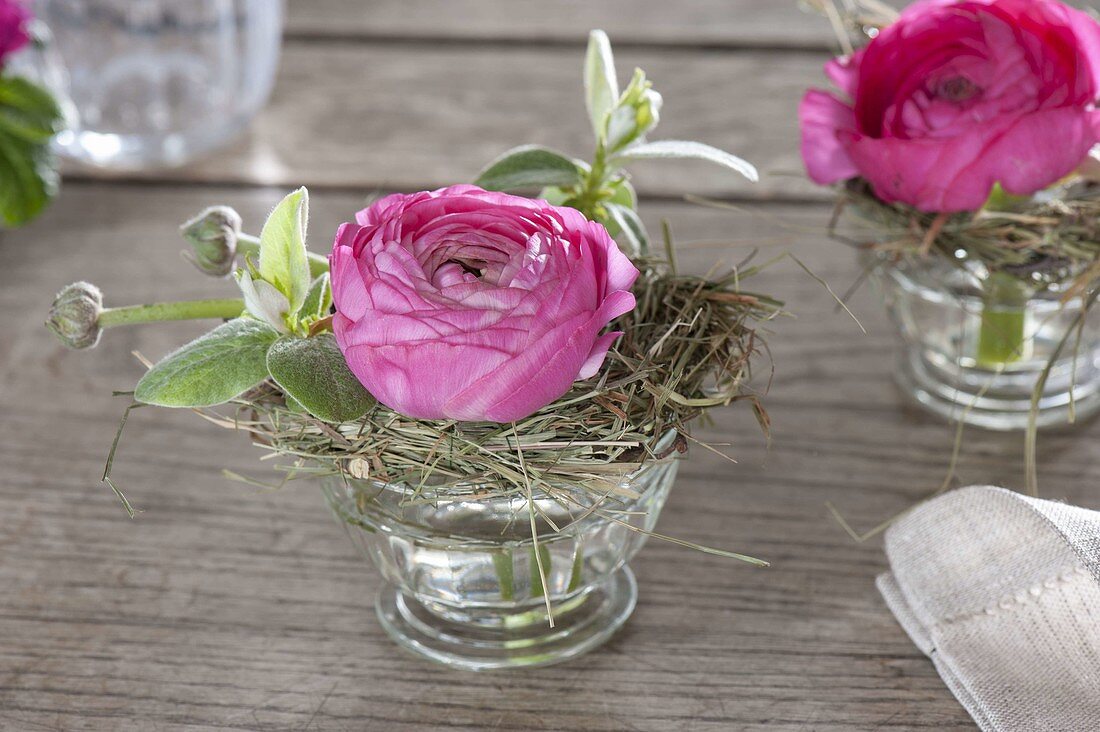 Kleine Straeusschen mit Ranunculus (Ranunkeln) und Zweigen von Malus