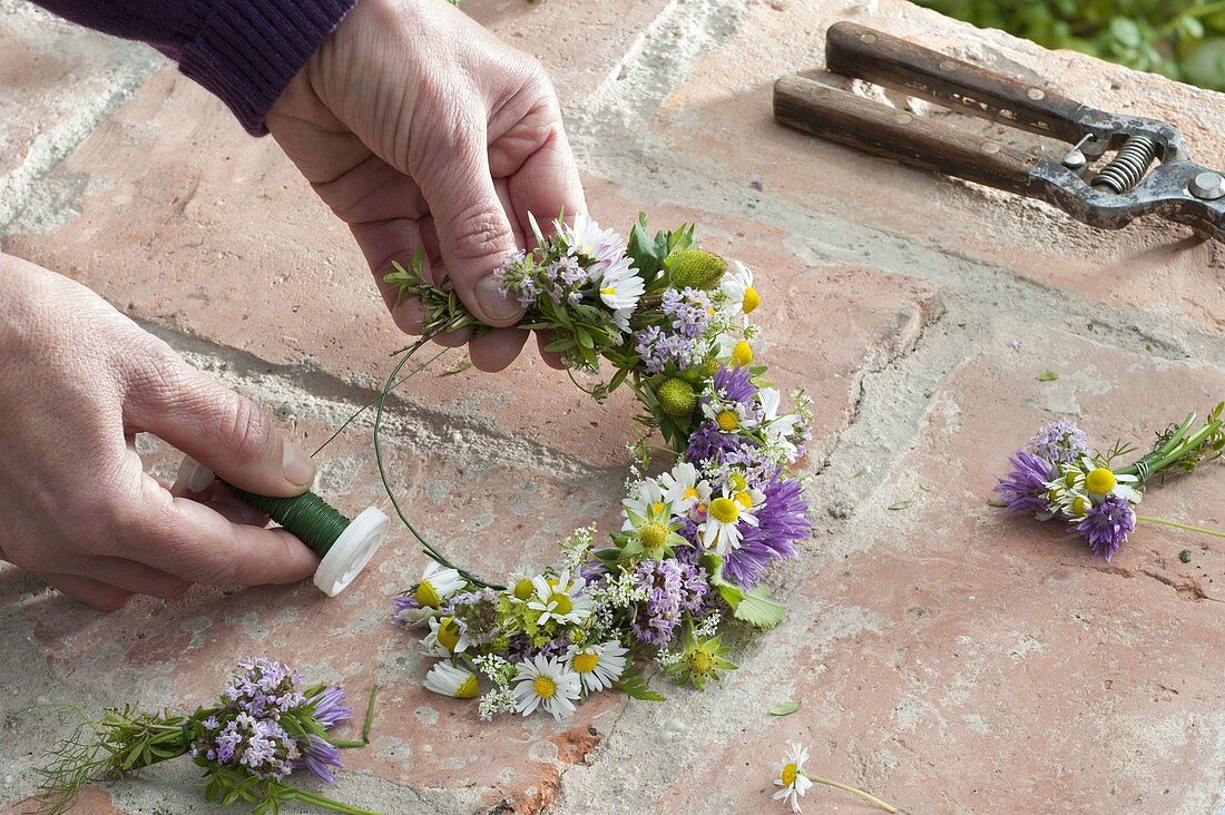 Making a wreath of flowering herbs and strawberries