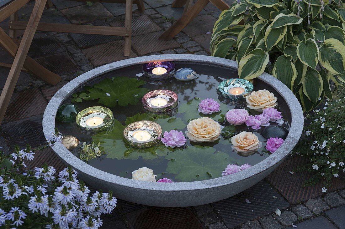 Bowl of floating rose petals and candles