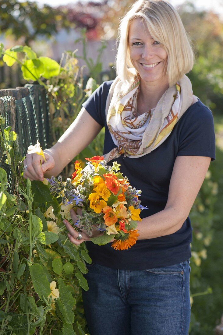Woman picking summer flowers bouquet with edible flowers
