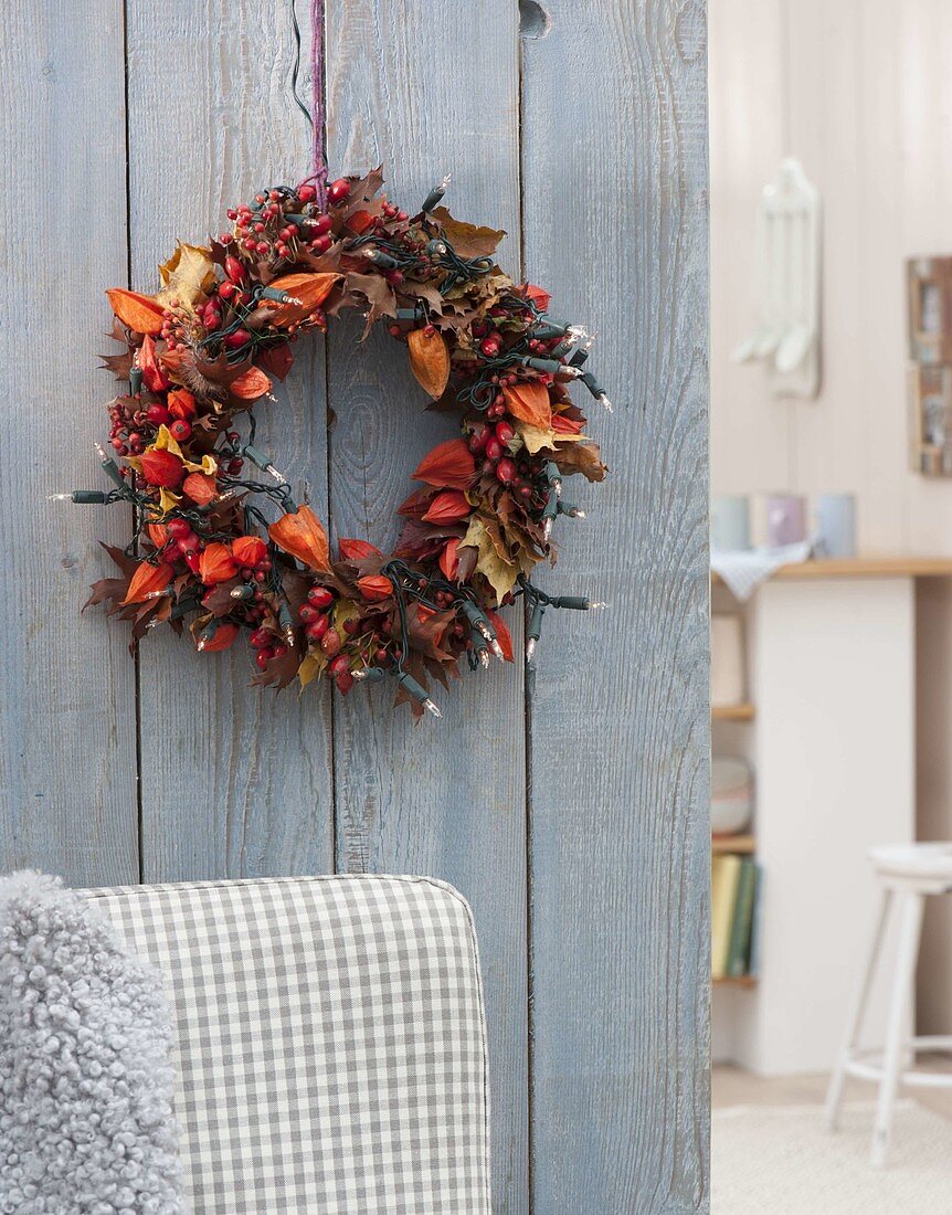 Leaf wreath with Physalis (lampions), Rosa (rose hips) and fairy lights